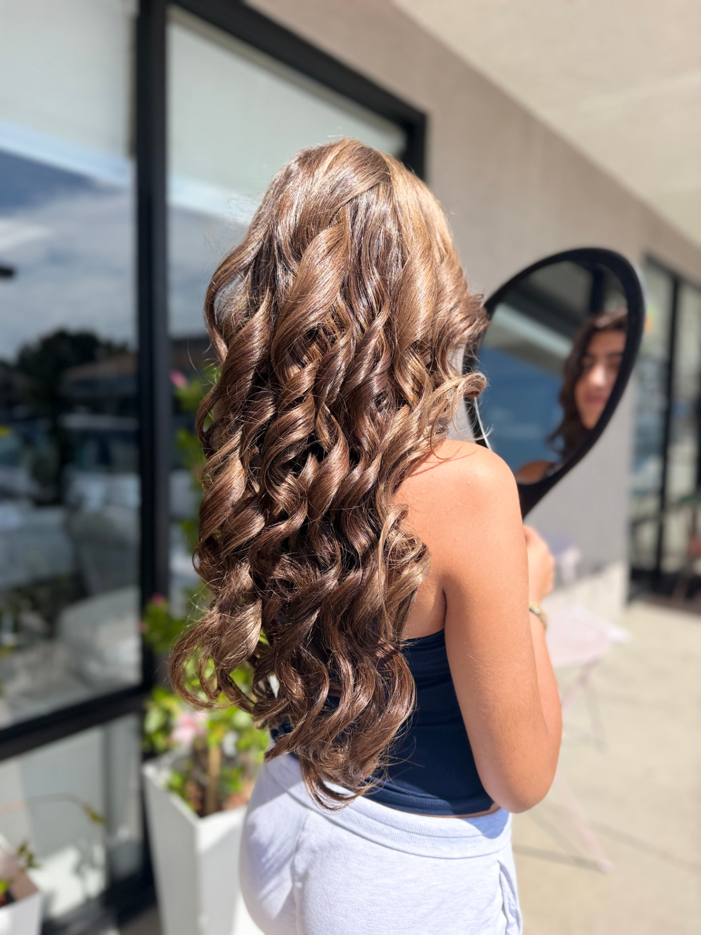 Woman with dimensional hair color and professionally styled waves at Roza Glam in Irvine